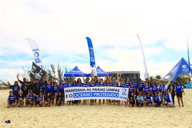 Voluntários do Ecosurf reunidos na praia com faixa em mutirão de limpeza