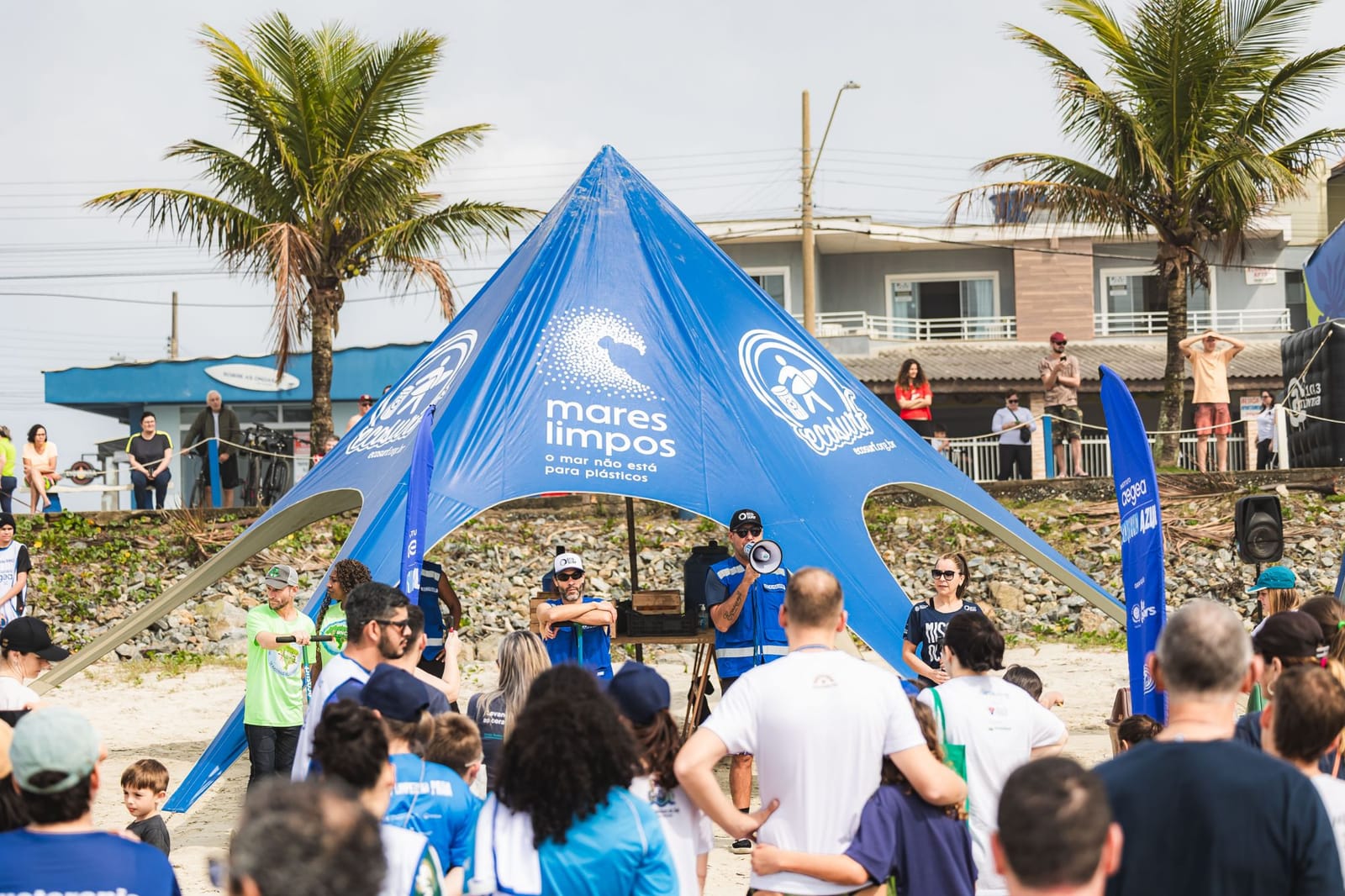 Facilitador do Ecosurf com megafone orienta os voluntários diante da tenda Mares Limpos