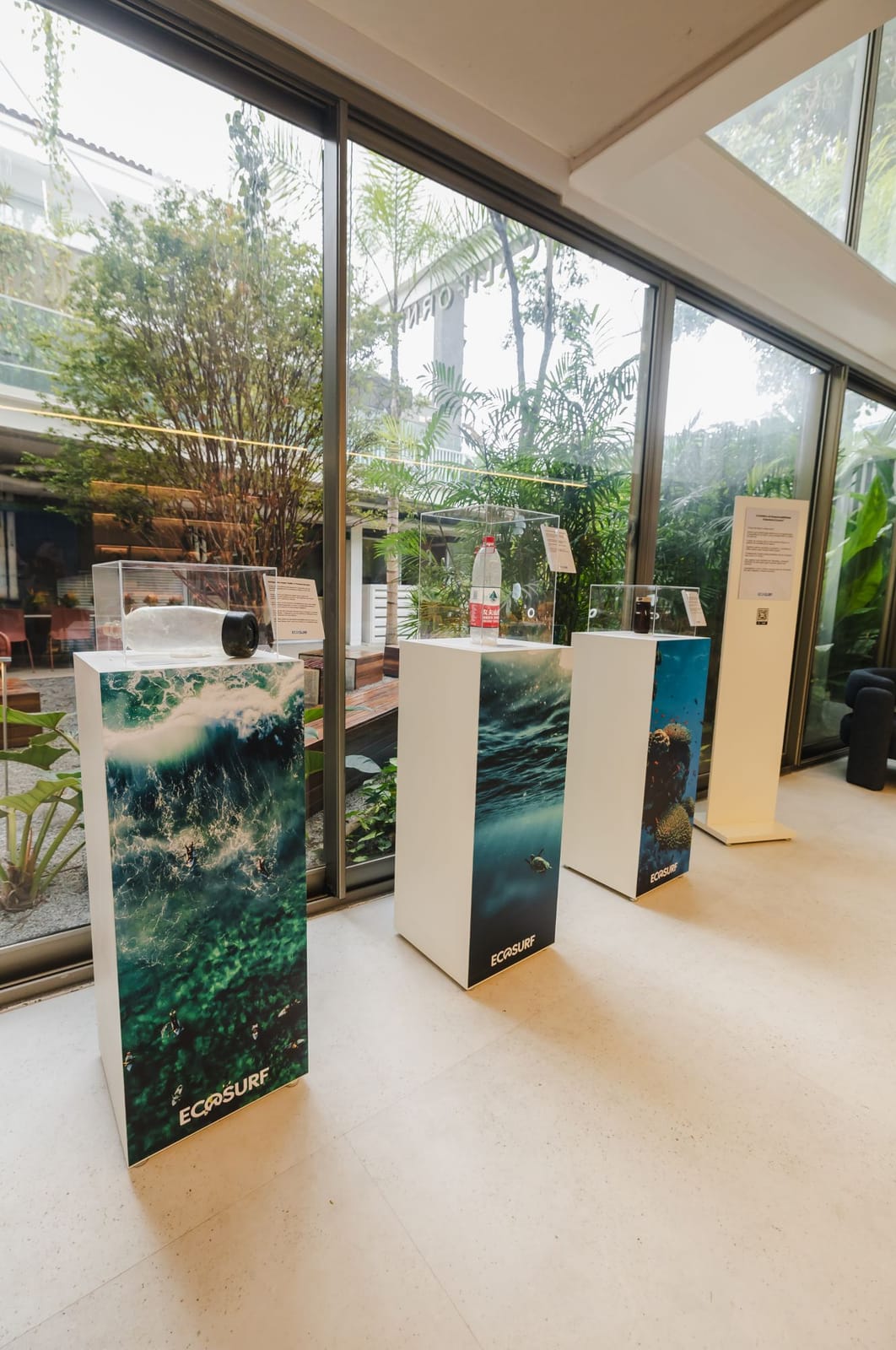Três totens da Mostra Re-Ocean com peças do acervo em cúpulas de acrílico e painel de apresentação