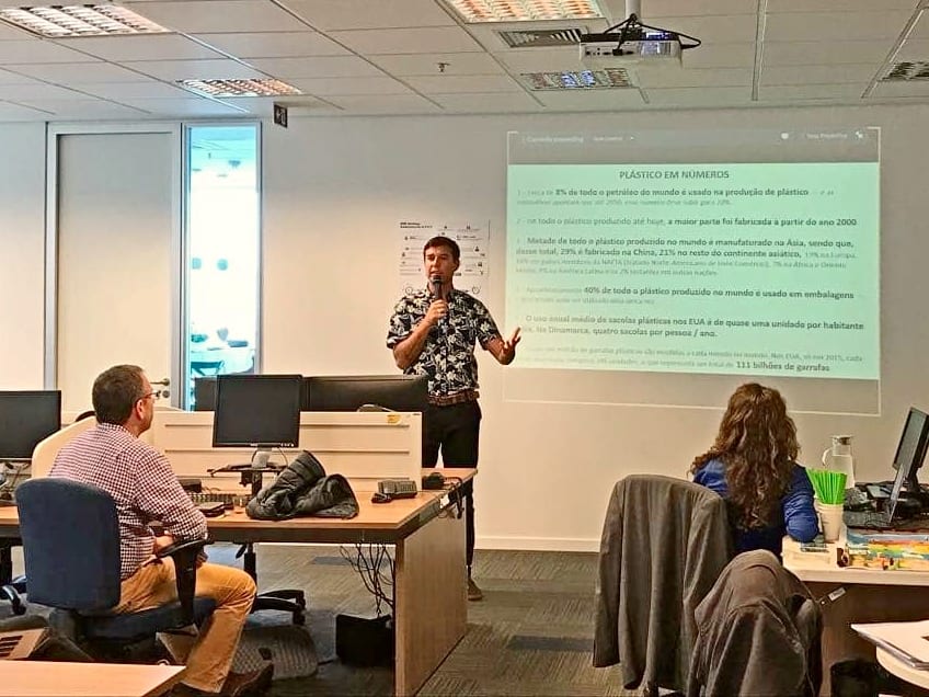 João Malavolta apresenta o slide Plástico em números para uma equipe em um escritório
