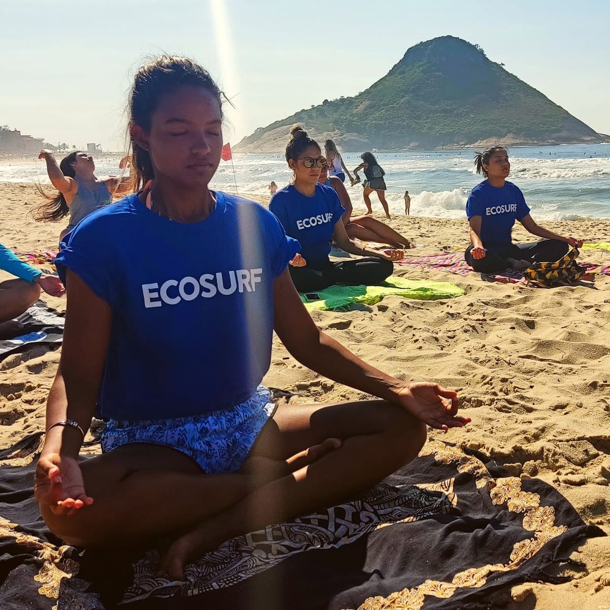 Voluntárias do Ecosurf em meditação na areia da praia