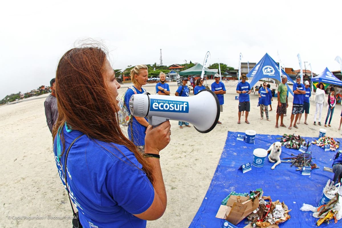 Voluntária do Ecosurf com megafone orientando um mutirão na praia
