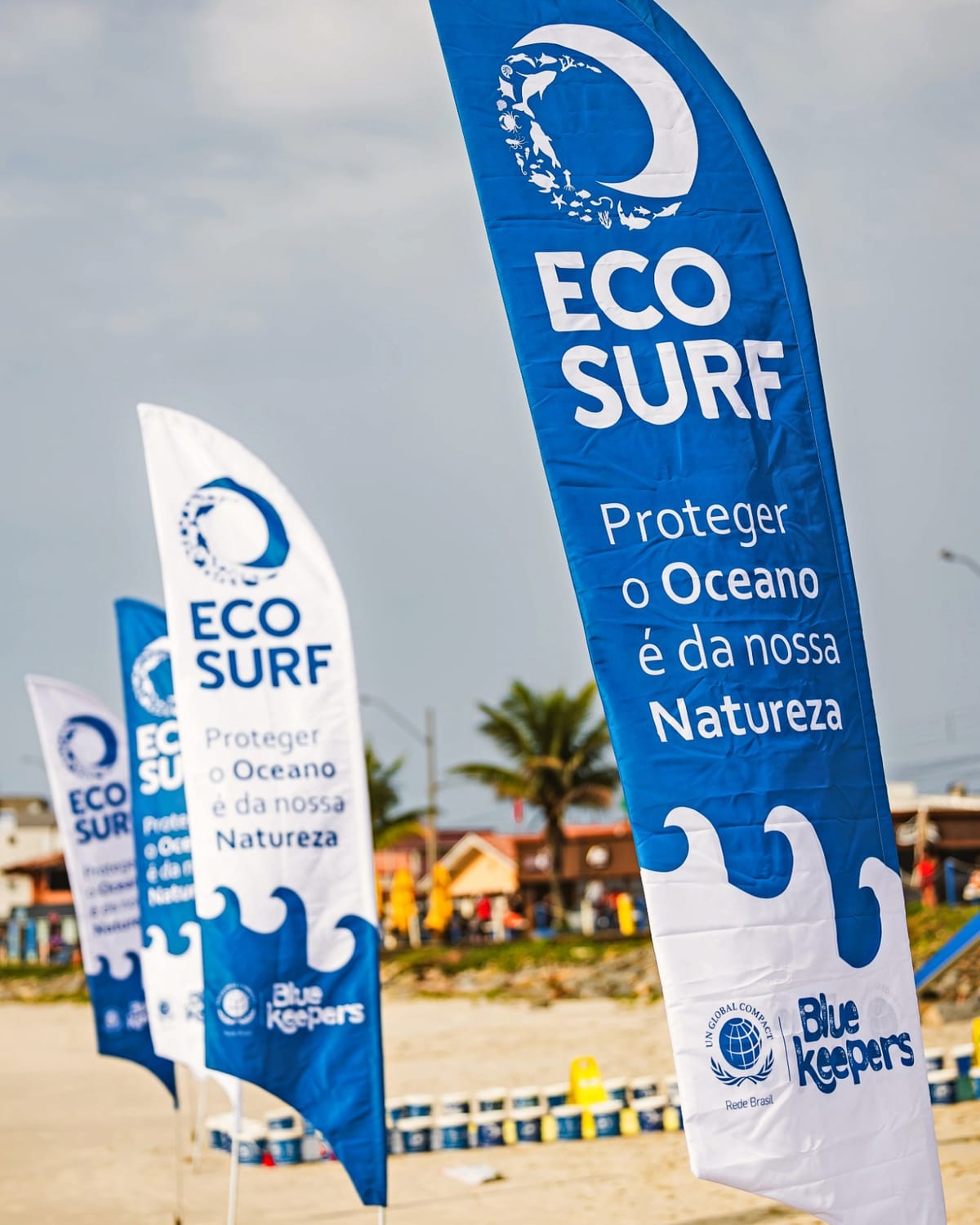 Bandeiras do Ecosurf na praia com a frase Proteger o Oceano é da nossa Natureza