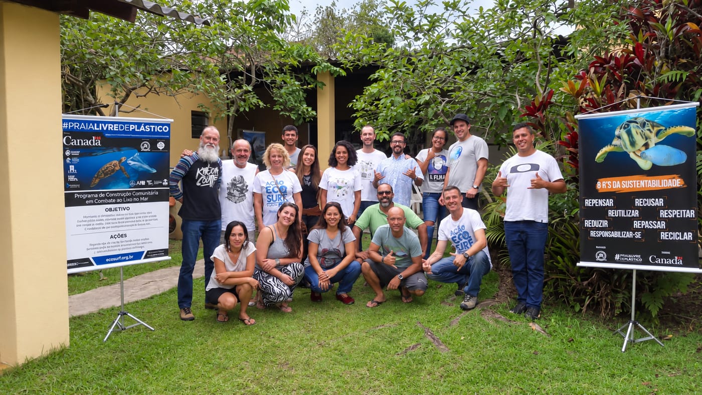 Participantes do #PraiaLivreDePlástico reunidos no jardim, ao lado dos banners do programa